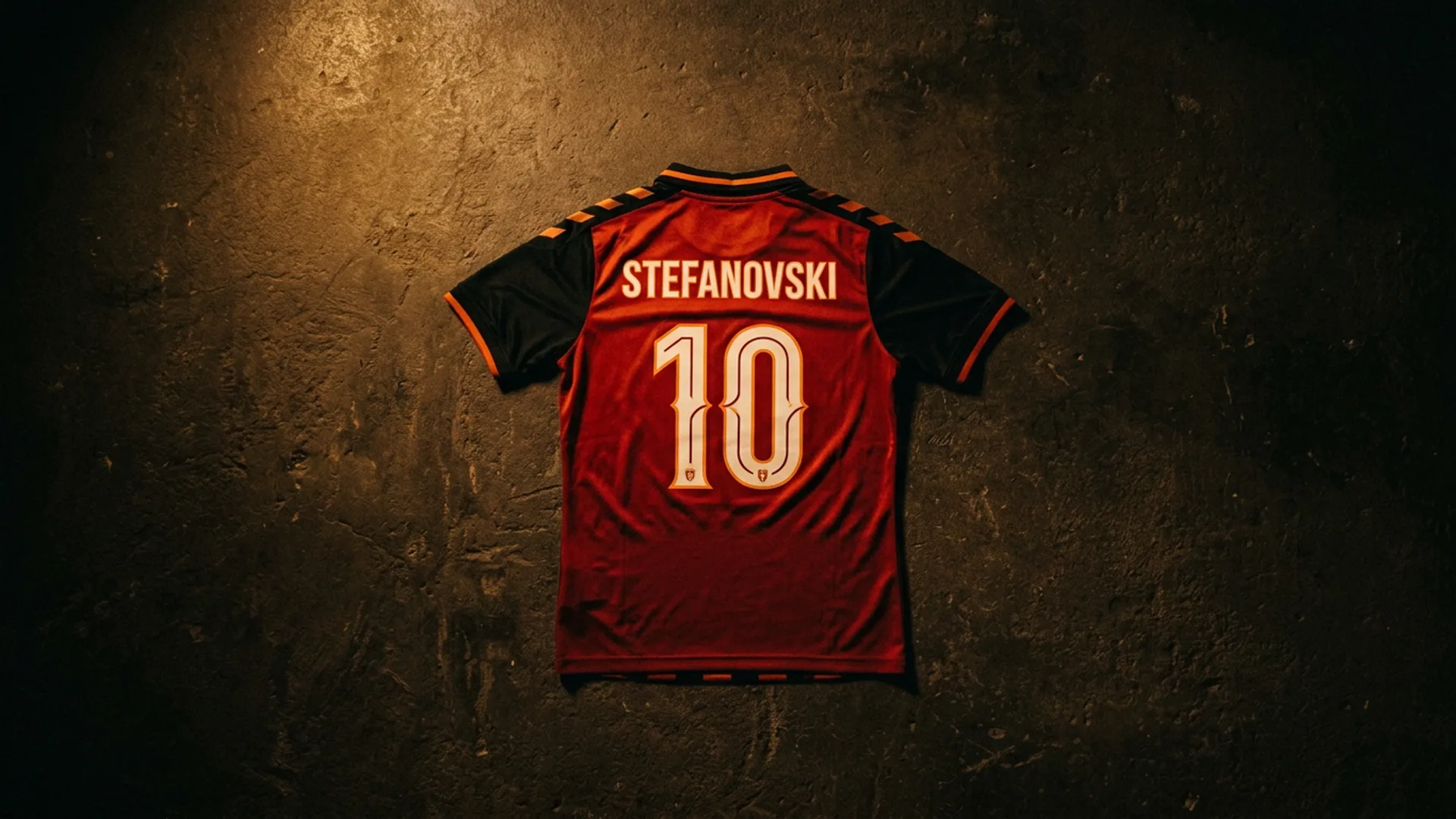 A custom football shirt laid flat on a dark concrete surface, lit by warm amber light